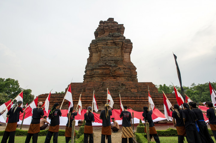 Sejumlah peserta kirab mengibarkan bendera Merah Putih saat Kirab 'Getah Getih' atau Merah Putih dalam rangka memperingati Hari Jadi ke-723 Kerajaan Majapahit di areal Candi Brahu, Trowulan, Mojokerto, Jawa Timur, Sabtu (12/11/2016)