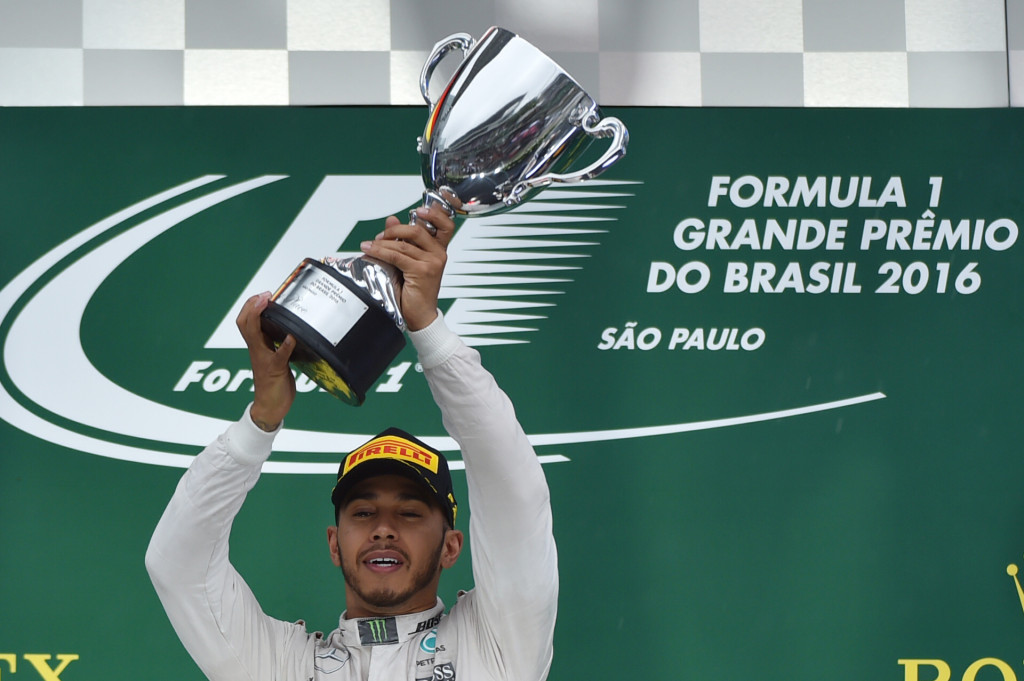 Hamilton mengangkat trofi kemenangan usai menang di GP Brasil