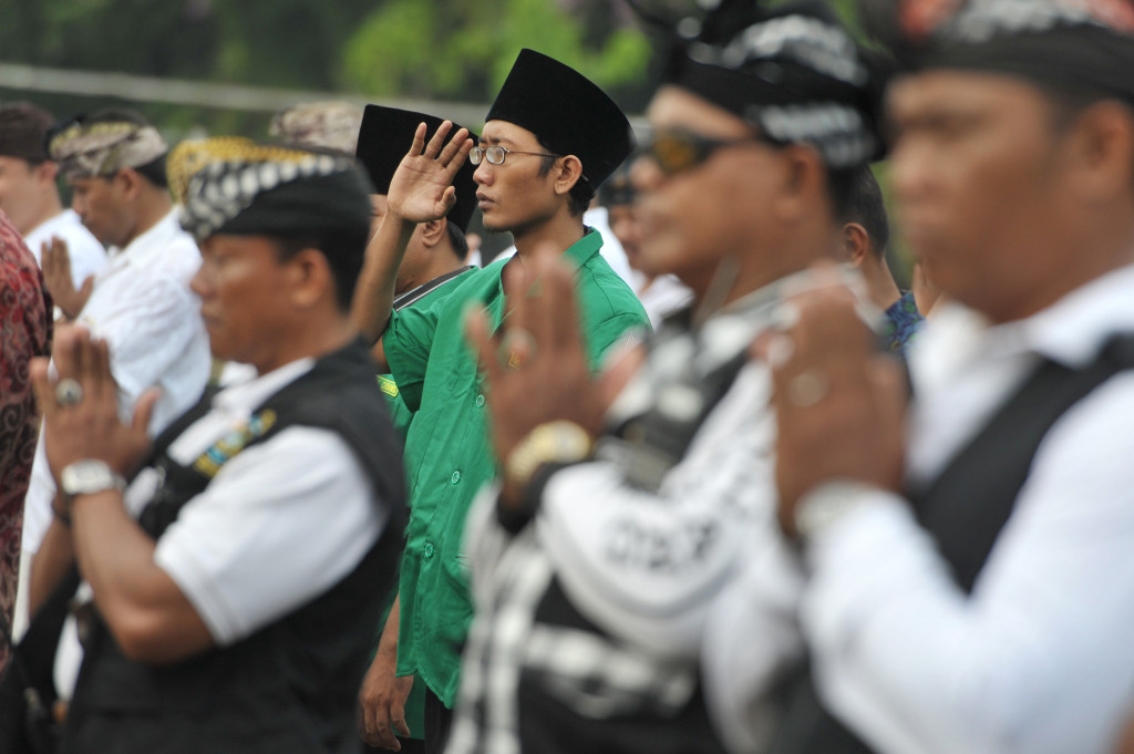 Anggota Gerakan Pemuda Ansor Bali bersama anggota pengamanan adat Bali atau Pecalang memberi penghormatan saat apel kebhinnekaan di Denpasar, Bali, Selasa (15/11/2016)
