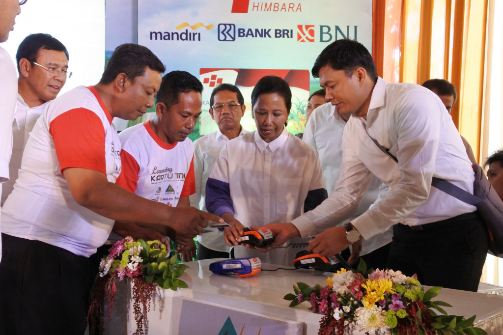 Menteri BUMN Rini Soemarno (kedua kanan) membantu petani cara menggunakan kartu tani di Pabrik Gula (PG) Asembagus, Situbondo, Jawa Timur, Rabu (16/11/2016)