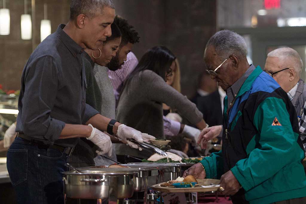 Sambil berbincang dengan para vetaran, Obama membagikan potongan ayam kalkun lengkap dengan sausnya.