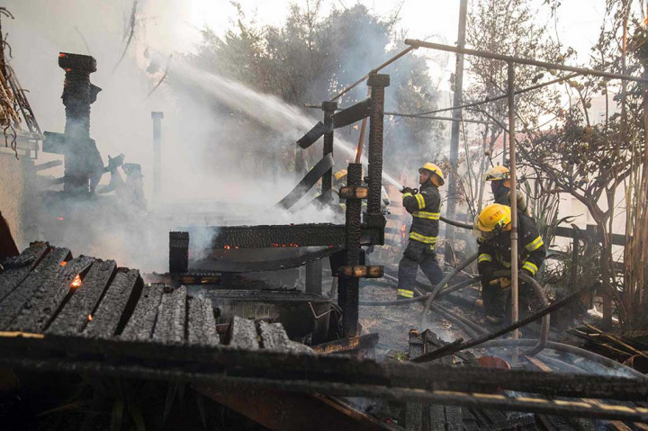 Petugas berusaha memadamkan api yang menghanguskan perumahan warga di Haifa.
