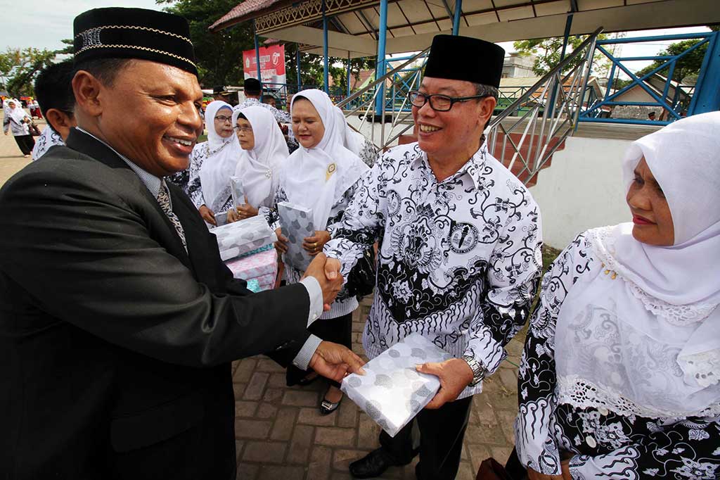 Kepala Dinas Pendidikan dan Olahraga Kota Lhokseumawe Rusli menyerahkan kado kepada pensiunan guru, pahlawan tanpa tanda jasa pada upacara memperingati Hari Guru Nasional (HGN) di Lapangan Hiraq, Lhokseumawe, Aceh, Jumat (25/11/2016). ANTARA/Ramhad