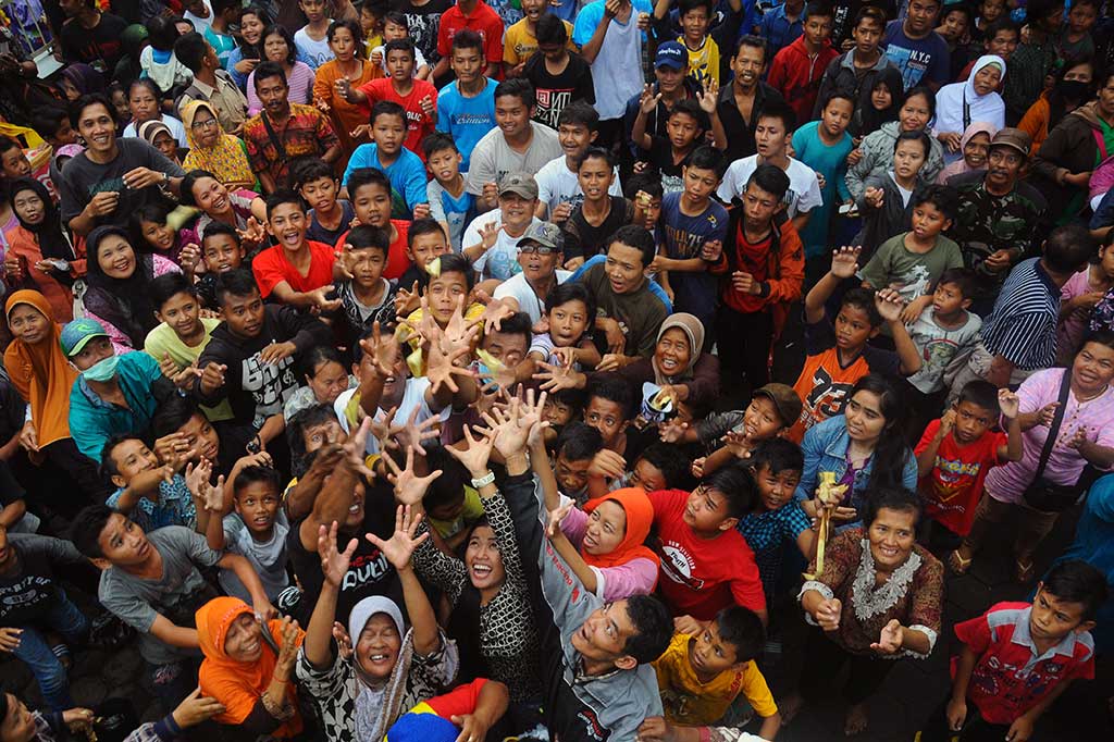 Warga berebut apem keong mas yang disebar.