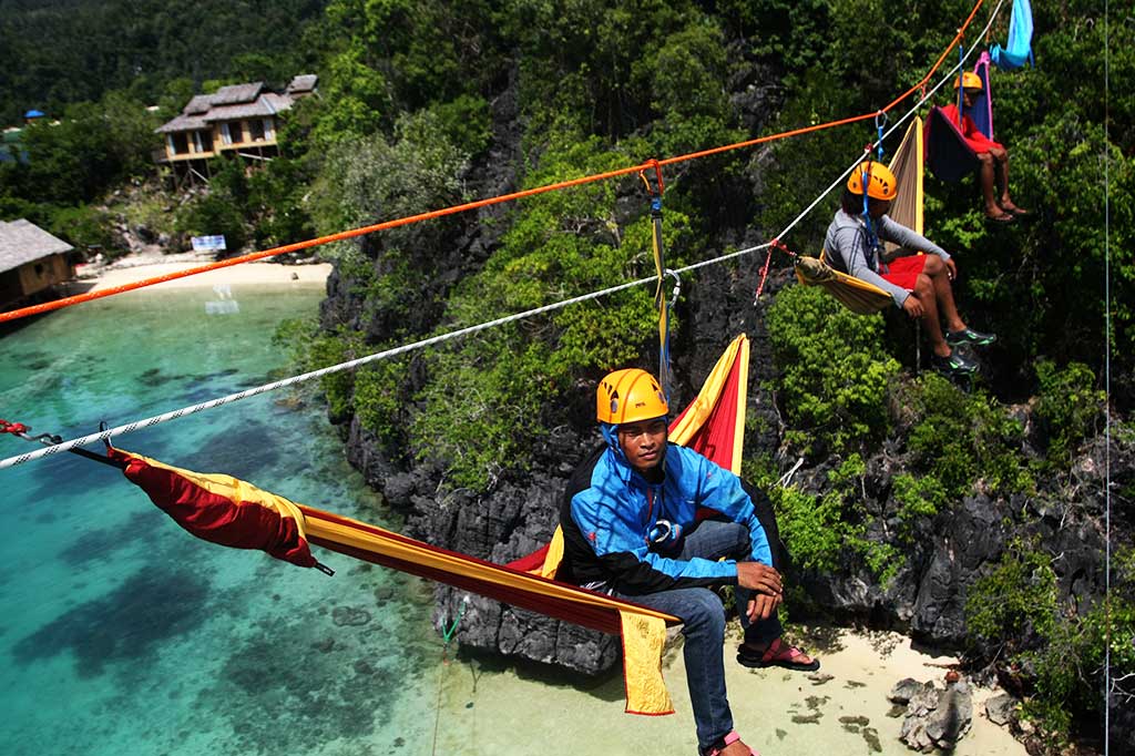 Tiga penggemar panjat tebing tengah menikmati sensasi di atas 'hammock' di puncak Pulau Labengki, Konawe Utara, Sulawesi Tenggara, Jumat (25/11/2016). 