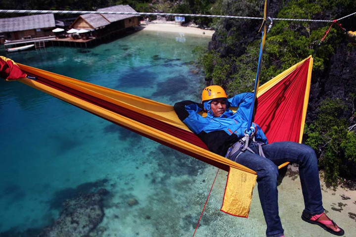 Seorang penggemar panjat tebing tengah bersantai di atas 'hammock' di puncak Pulau Labengki, Konawe Utara.