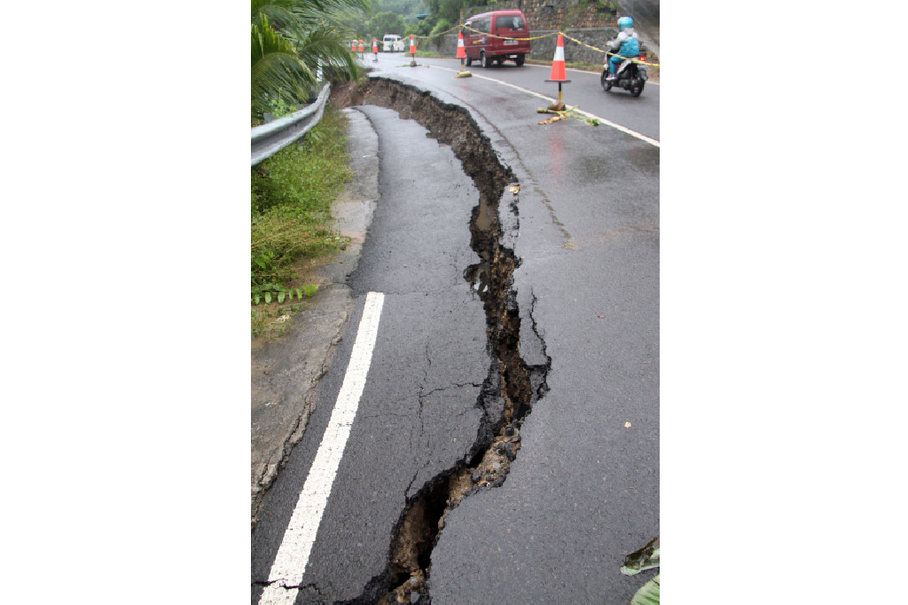 Jalan retak akibat amblesnya tanah lereng.