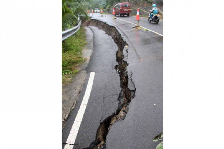 Jalan retak akibat amblesnya tanah lereng.