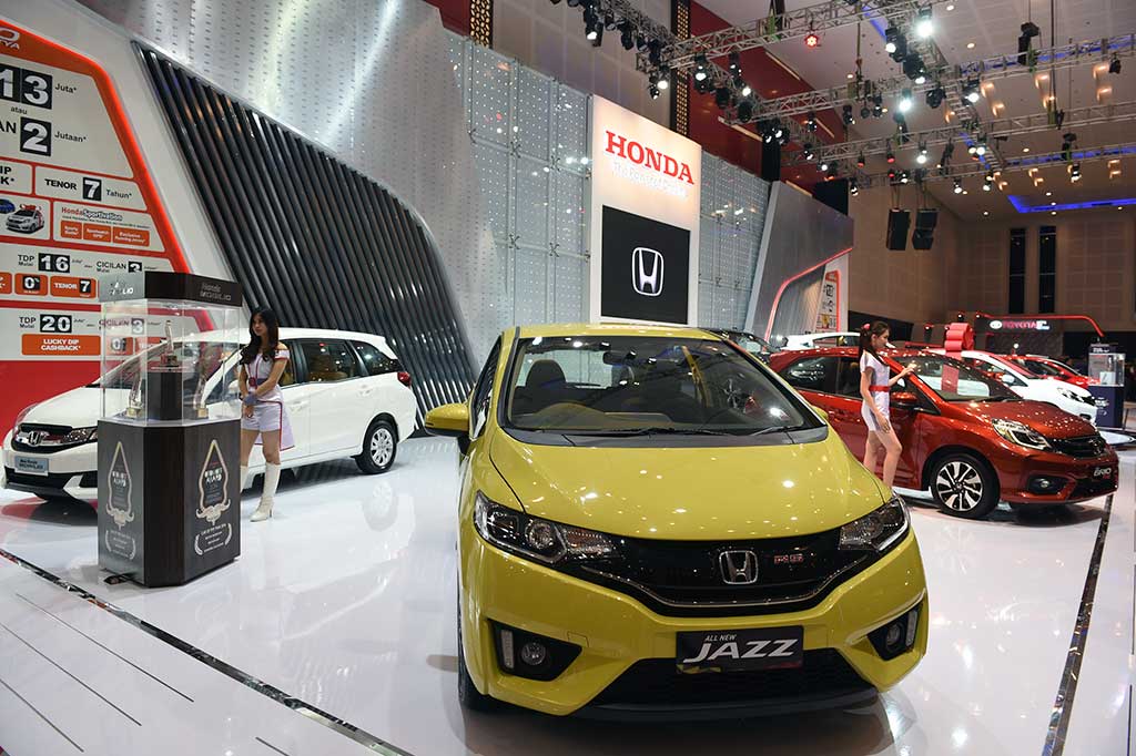 Model menawarkan mobil kepada pengunjung pada Pameran Otomotif Surabaya di Surabaya, Rabu.