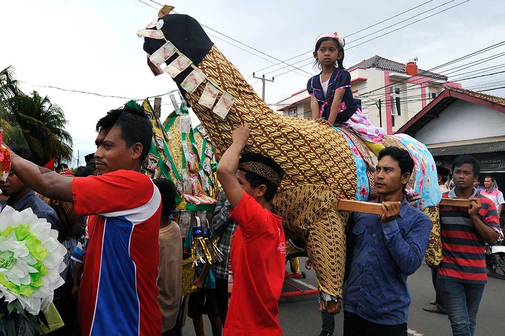 Warga menggotong replika unta saat pawai pernak-pernik 'Panjang' di Pejaten, Serang, Banten.