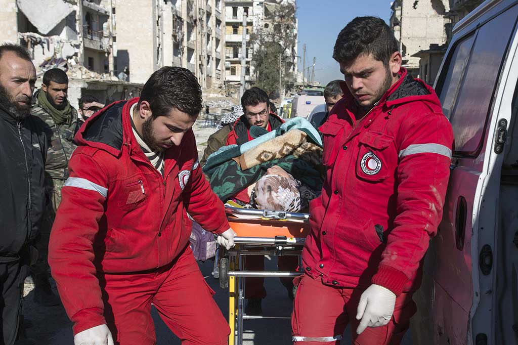Staf Bulan Sabit Merah menandu warga yang terluka untuk dievakuasi dari wilayah yang dikuasai pemberontak di Aleppo.