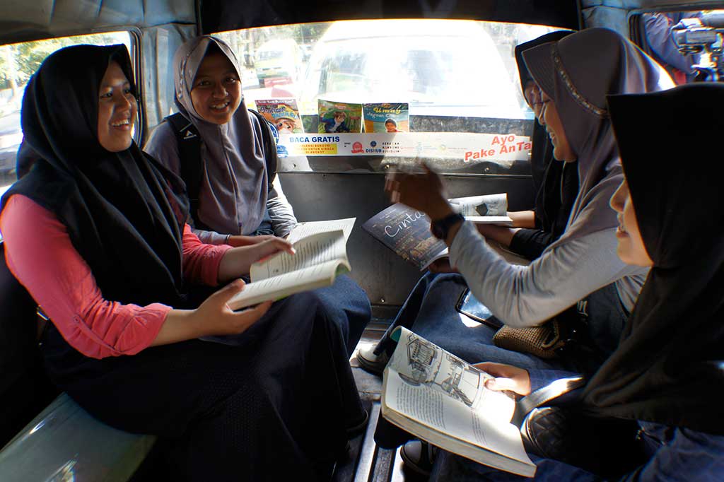 Penumpang membaca buku di dalam angkot saat peluncuran Angkot Pintar di Bandung.