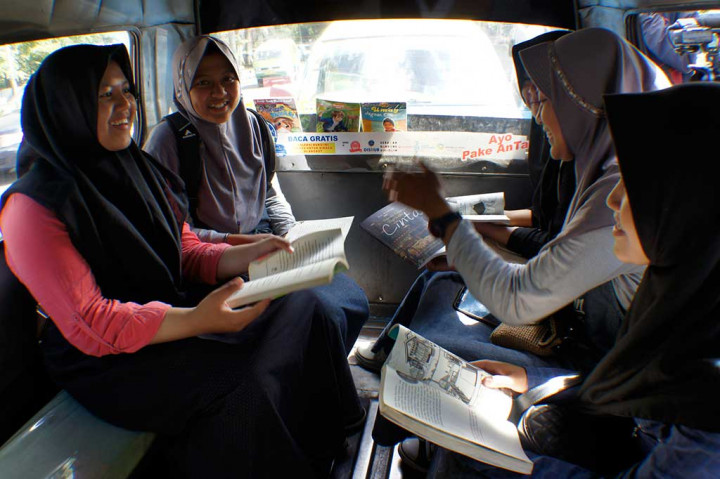 Penumpang membaca buku di dalam angkot saat peluncuran Angkot Pintar di Bandung.