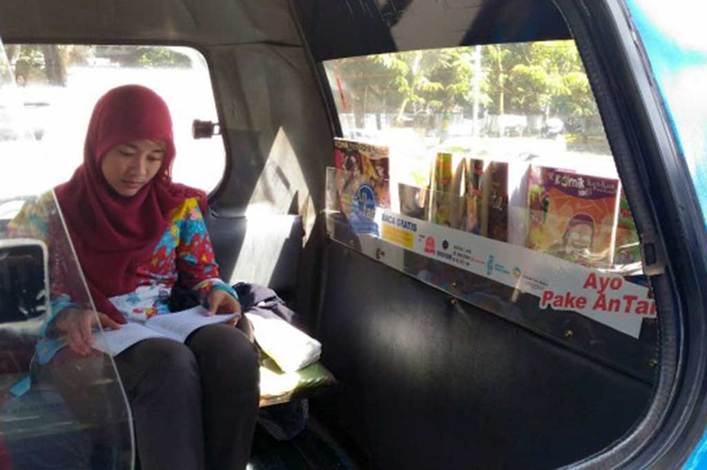 Penumpang Angkot Pintar tengah membaca buku yang disediakan di dalam armada tersebut. MTVN/Roni Kurniawan