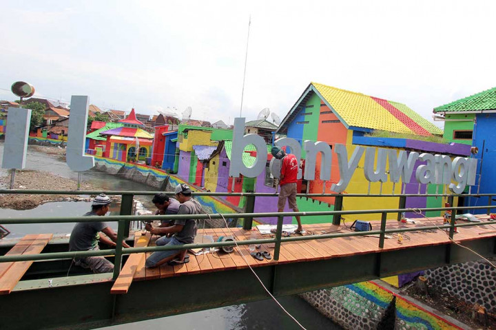 Pekerja menyelesaikan pembangunan jembatan penyeberangan di kampung warna warni di Kalilo, Singonegaran, Banyuwangi, Jawa Timur, Jumat (16/12/2016).