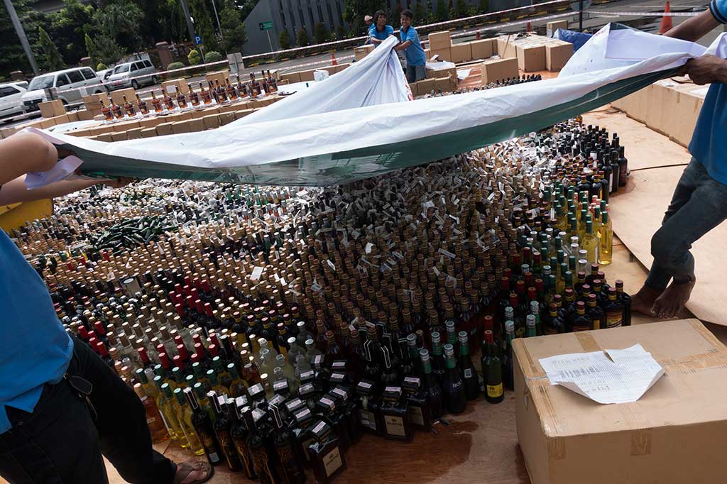 Petugas menutup ribuan rokok dan minuman keras tanpa label cukai yang akan dimusnahkan di halaman Kantor Pusat Ditjen Bea dan Cukai, Jakarta, Kamis (22/12/2016).