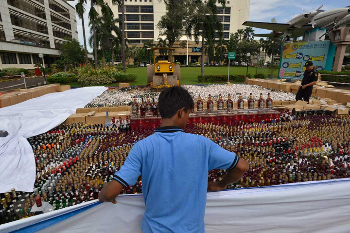 Petugas berada di antara ribuan minuman keras dan rokok tanpa label cukai yang akan dimusnahkan di halaman Kantor Pusat Ditjen Bea dan Cukai, Jakarta, Kamis (22/12/2016).