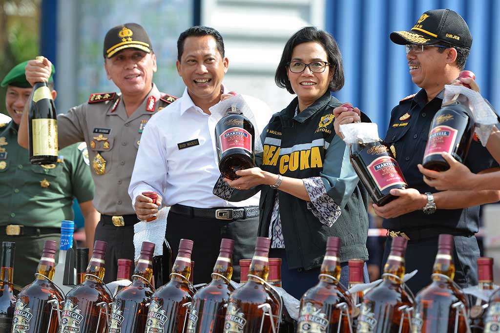 Menteri Keuangan Sri Mulyani (kedua kanan) bersama Kepala BNN Komjen Budi Waseso (kedua kiri), Dirjen Pajak Heru Pambudi (kanan), dan Kapolda Metro Jaya Irjen Pol M. Iriawan menunjukkan botol minuman keras tanpa pita cukai sebelum pemusnahan di halaman kantor pusat DJBC, Jakarta, Jumat (23/12/2016).