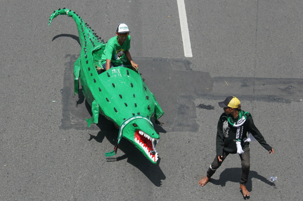 Seorang suporter Persebaya mengendarai replika Buaya saat Parade Bela Persebaya.