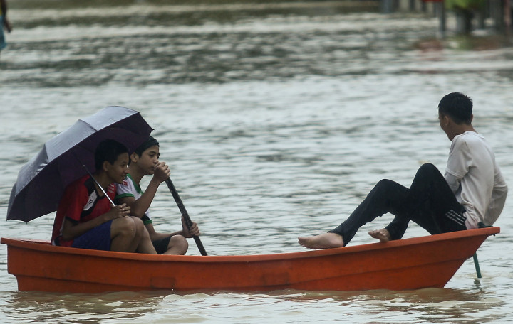 Tiga orang anak bermain perahu di tengah banjir. Hujan lebat berlangsung selama empat hari berturut-turut memicu banjir. 
