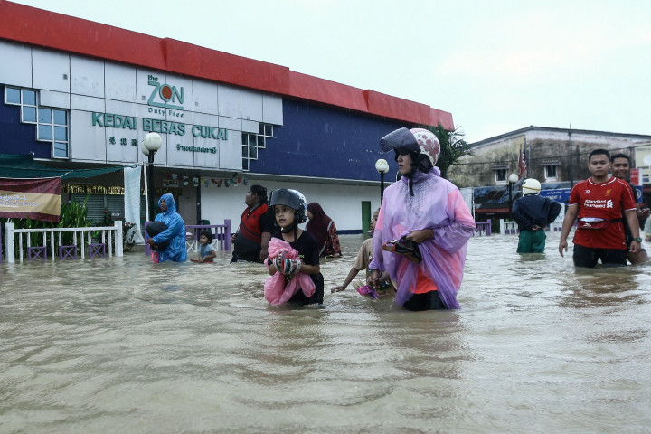 Warga melintas di depan sebuah toko bebas cukai. Ketinggian banjir rata-rata mencapai pinggang orang dewasa.