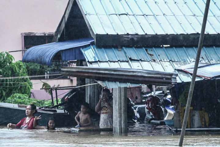 Sekelompok warga berteduh di teras rumahnya yang terendam banjir. Banjir terjadi merata di hampir semua wilayah pesisir timur Malaysia.