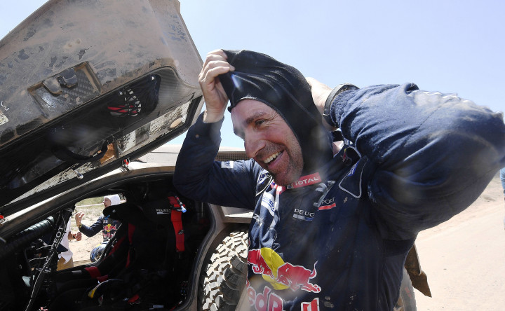 Stephane Peterhansel tersenyum lega setelah berhasil menyelesaikan etape 2. Pereli andalan tim Peugeot ini adalah veteran dalam ajang reli bergengsi kelas dunia. 