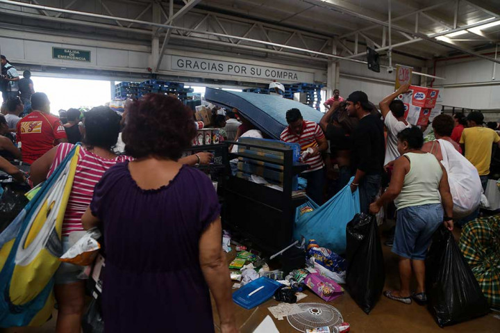 Para penjarah memakai kantong-kantong besar untuk membawa barang jarahan.