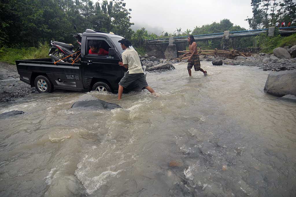 Warga mendorong mobil yang terjebak saat melintasi Sungai Kaliarus di Desa Cawitali. Ribuan warga di dua desa harus menerjang arus sungai yang deras akibat jembatan sepanjang 25 meter ambruk.