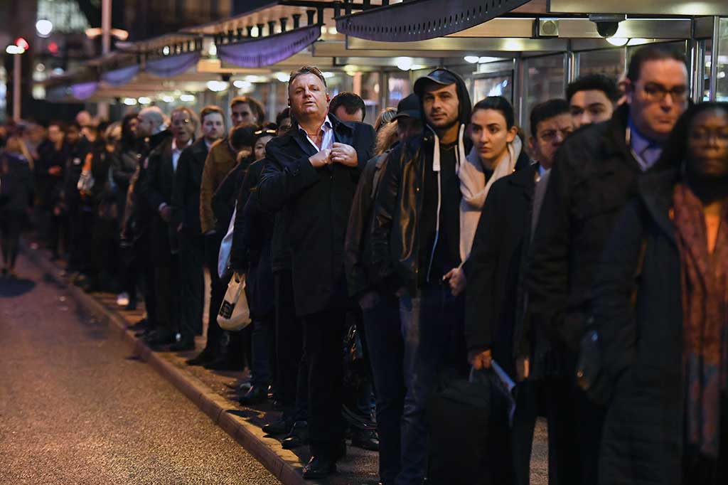 Ratusan calon penumpang kereta komuter beralih menggunakan moda bus dan dengan sabar menunggu di sebuah halte dekat Stasiun Victoria, London.