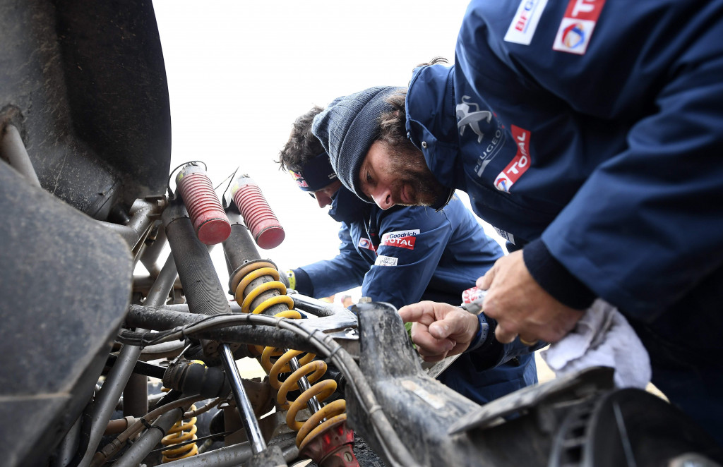 Cyril Despres (kiri) and David Castera memeriksa kondisi suspensi Peugeot-nya di barak pereli di Uyuni, Bolivia. 