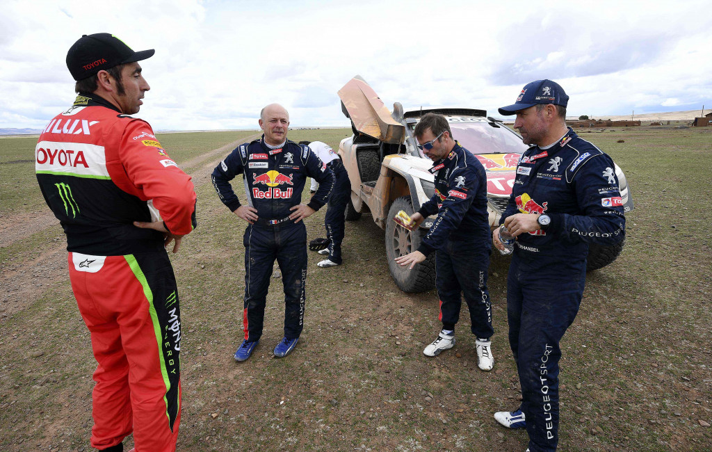 Pereli tim Toyota, Nani Roma (Spanyol) bercanda dengan Jean Paul Cottret, Sebastien Loeb dan   driver Stephane Peterhansel dari tim Peugeot di pos peristirahatan etape 8. Setelah etape 6, panitia mengumumkan membatalkan etape 9 yang jalur tertimbun longsor akibat hujan lebat.
