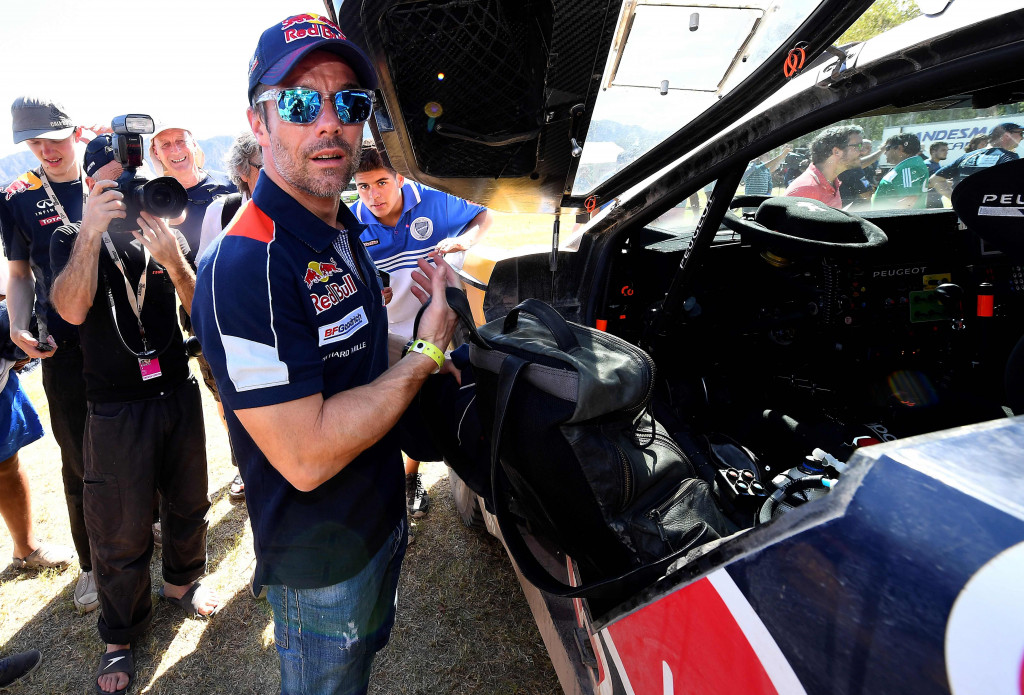 Sebastien Loeb (Prancis) membersihkan kabin Peugeot-nya untuk menghadapi etape berikutnya.