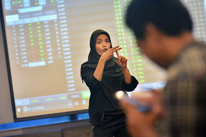 Mentor menggunakan bahasa isyarat saat menerangkan kepada penyandang disabilitas dari YDMI dalam Sekolah Pasar Modal bagi Difabel di BEI, Jakarta.