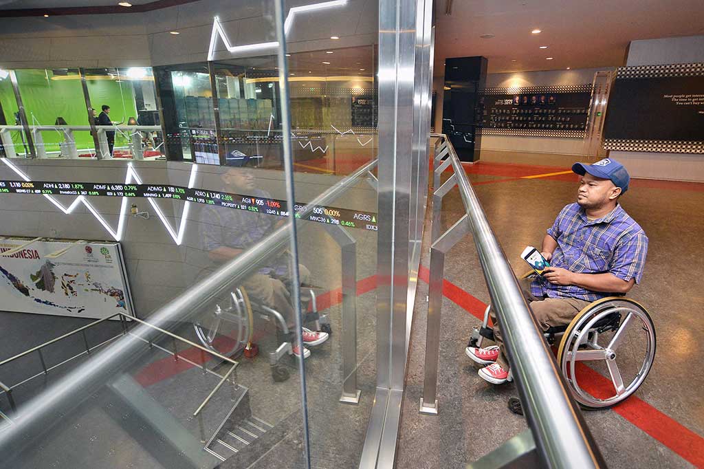 Penyandang disabilitas dari YDMI mengamati pergerakan harga saham saat mengikuti Sekolah Pasar Modal bagi Difabel di BEI, Jakarta. 