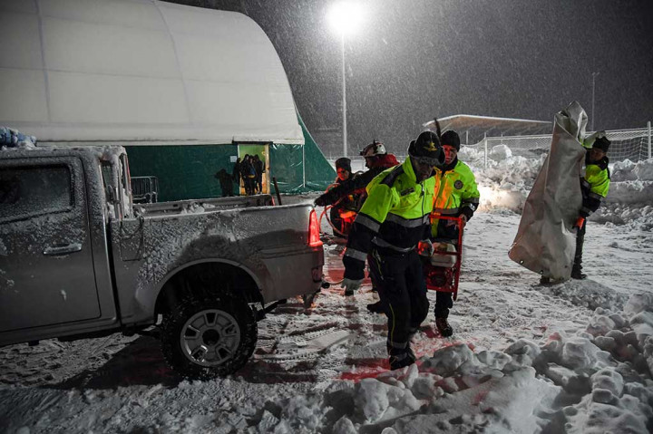 Anggota Perlindungan Sipil Italia (Protezione Civile) membawa sebuah generator listrik untuk menerangi sebuah tenda besar di lapangan olahraga di Montereale.