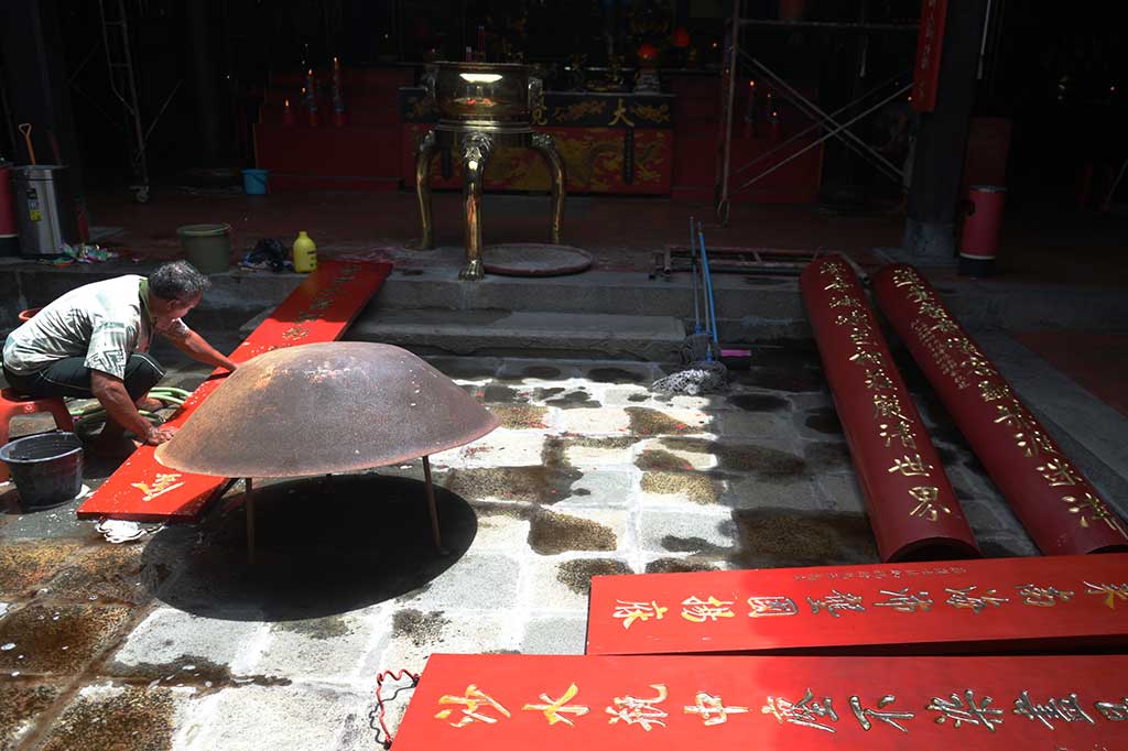 Pekerja membersihkan papan bertuliskan huruf Tiongkok di Klenteng Tay Kak Sie Semarang, Jawa Tengah, Selasa (24/1/2017). 