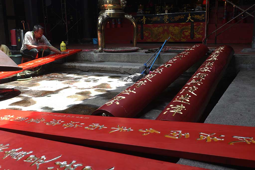 Pekerja membersihkan papan bertuliskan huruf Tiongkok di Klenteng Tay Kak Sie Semarang.