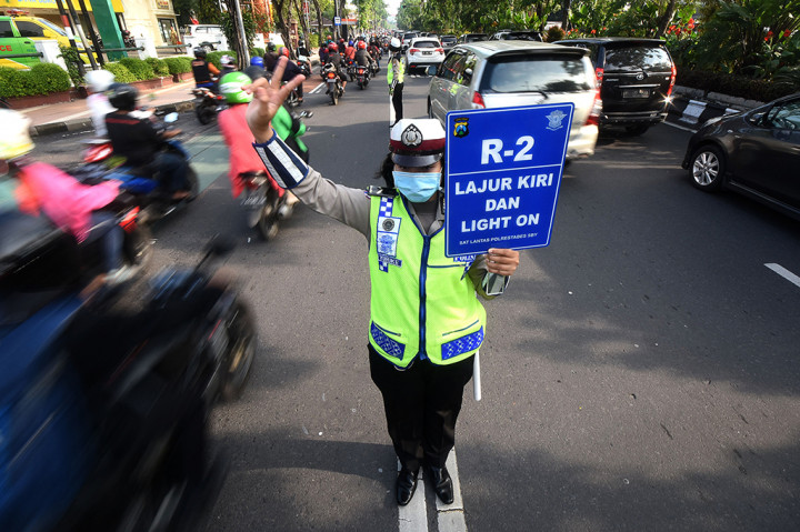 Seorang Polisi wanita (Polwan) Satlantas Polrestabes Surabaya mengatur kendaraan roda dua untuk selalu di jalur kiri (kanalisasi) di kawasan Raya Darmo, Surabaya, Jawa Timur.