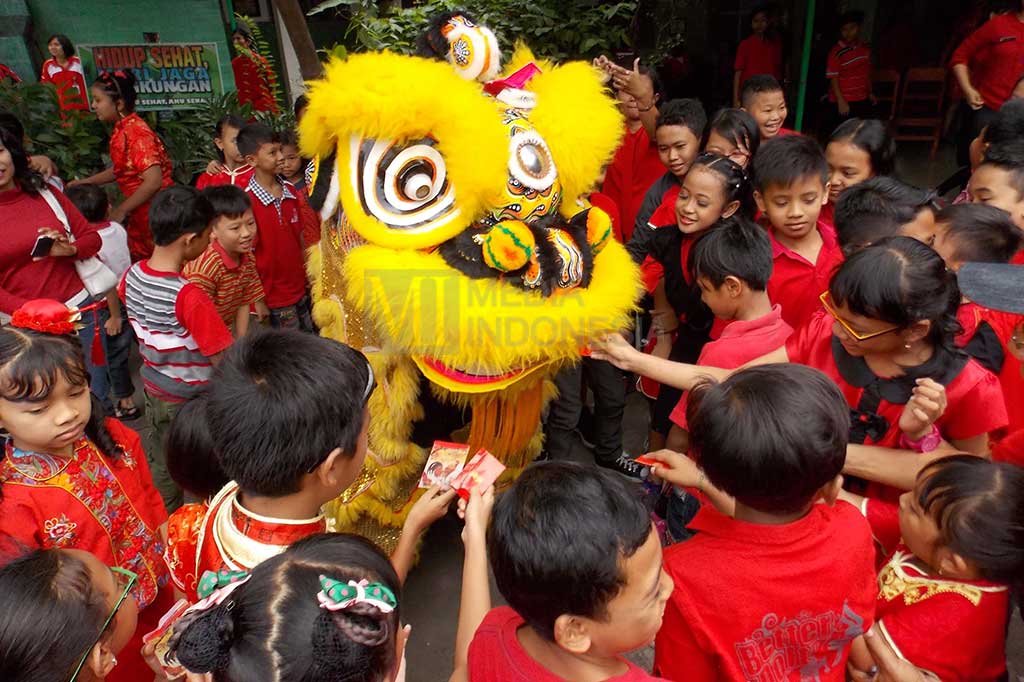 Siswa SD Warga Surakarta, Jawa Tengah berebut memasukkan angpao ke mulut barongsai.