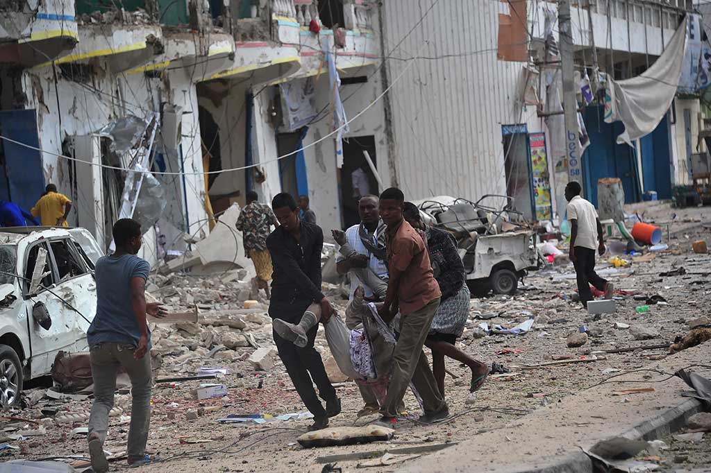 Warga mengevakuasi korban luka-luka akibat ledakan bom dan serangan terhadap hotel di Mogadhishu, Somalia, Rabu.