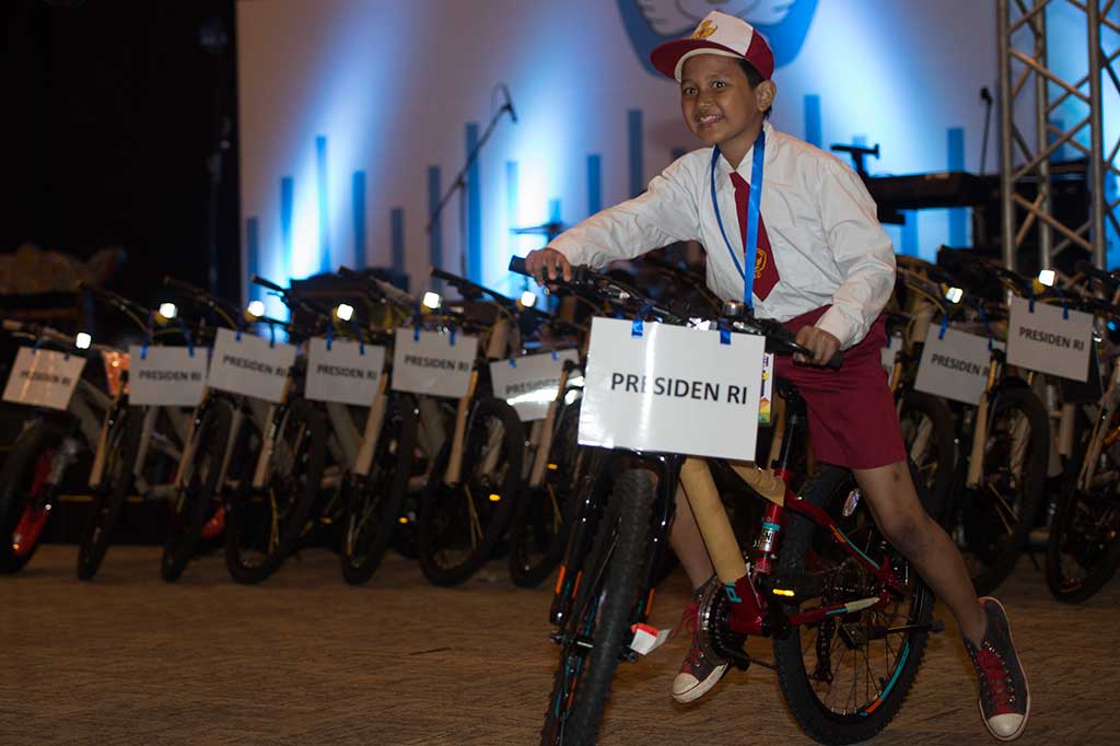 Seorang pelajar membawa hadiah sepeda setelah menjawab pertanyaan dari Presiden.