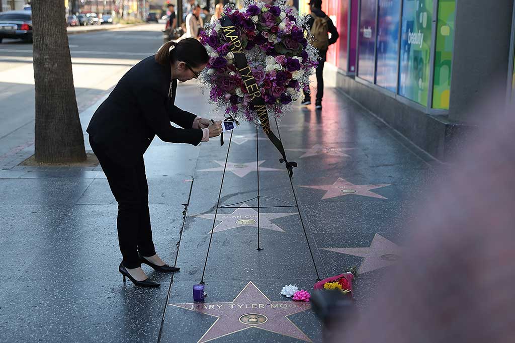 Seorang perempuan menuliskan pesan tanda duka cita di sebuah karangan bunga untuk mendiang aktris Mary Tyler Moore di Hollywood Walk of Fame, Hollywood, California, Rabu (25/1/2017) waktu setempat.