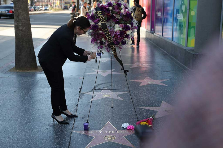 Seorang perempuan menuliskan pesan tanda duka cita di sebuah karangan bunga untuk mendiang aktris Mary Tyler Moore di Hollywood Walk of Fame, Hollywood, California, Rabu (25/1/2017) waktu setempat.