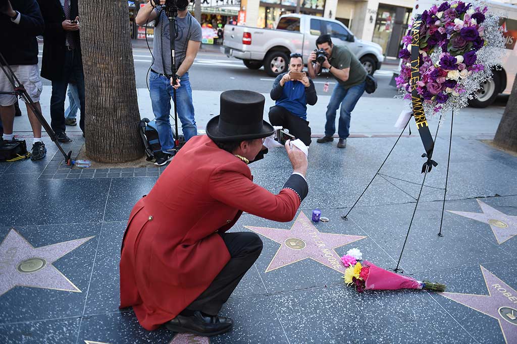 Seorang pria mengambil gambar karangan bunga yang diletakkan di bintang milik mendiang Mary Tyler Moore di Hollywood Walk of Fame, Hollywood.