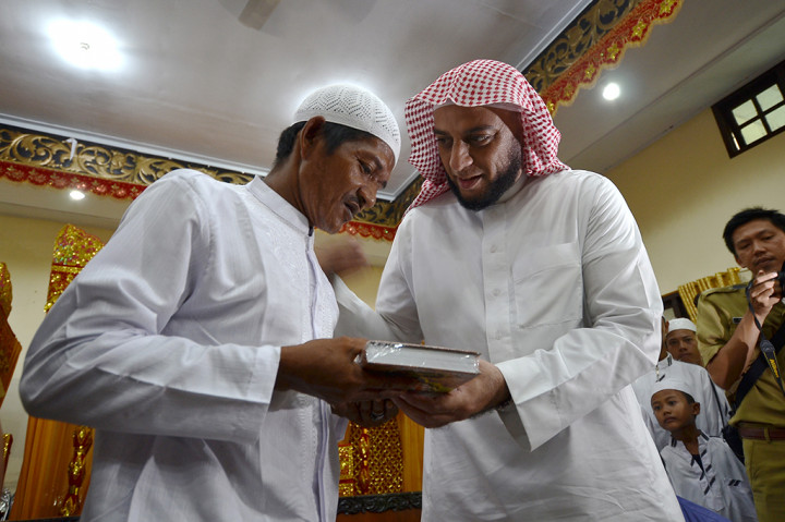 Syekh Ali Jaber (kanan) memberikan Alquran kepada salah seorang warga Suku Anak Dalam (SAD) yang bermukim di Desa Berumbung Bandung III atau kawasan sekitar Taman Nasional Bukit Dua Belas (TNBD) Jambi yang baru selesai membacakan dua kalimat syahadat di Balai Adat Tanah Pilih Kota Jambi.