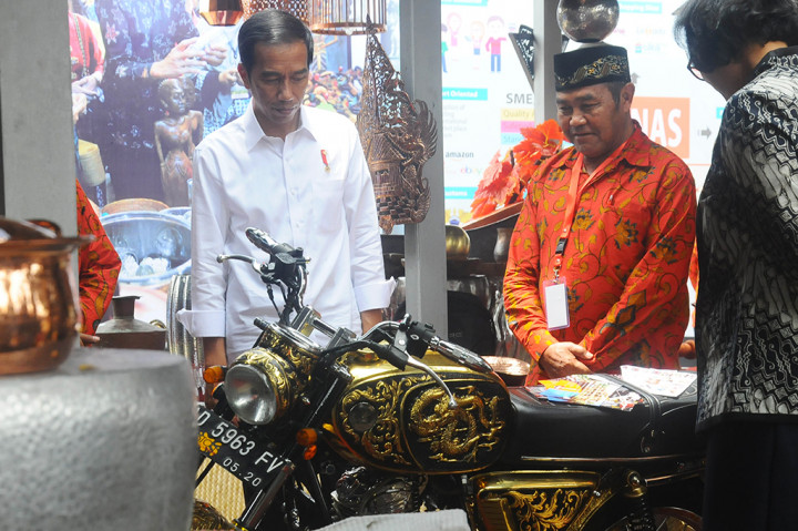 Presiden Joko Widodo (kiri) melihat hasil kerajinan tembaga saat peluncuran fasilitas kebijakan Kemudahan Impor Tujuan Ekspor untuk Industri Kecil dan Menengah (KITE IKM).