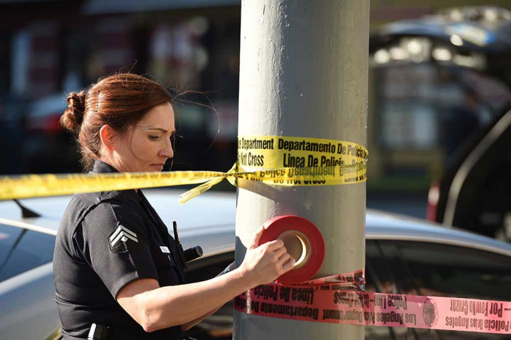 Seorang polisi wanita memasang garis polisi di luar Restoran 'Jack in the box', di Hollywood, California, Selasa, setelah polisi menembak  seorang pria bersenjata pisau yang menusuk beberapa pengunjung.