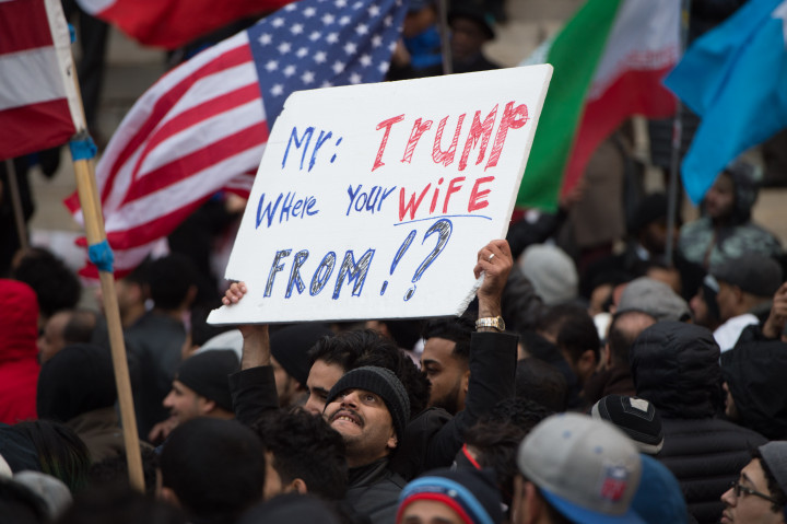 Poster unjuk rasa menyindir latar belakang istri Donald Trump yang diketahui merupakan imigran.