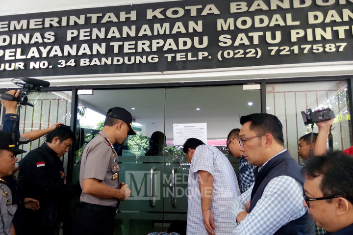Kapolrestabes Bandung Kombes Hendro Pandowo ditemani Wali Kota Ridwan Kami, membuka garis polisi yang terpasang di pintu utama kantor Dinas Penanaman Modal dan Pelayanan Terpadu Satu Pintu (DPMPTSP).